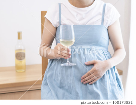 Pregnant woman holding a wine glass filled with wine 108173821