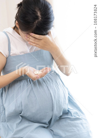 Image of a woman holding her head and holding medicine Image of a woman holding her head and holding medicine 108173824
