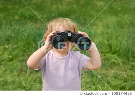 Little girl using binoculars in a forest. 2 years kid looking ahead. Smiling baby with spyglass. Adventure, Imagination, travel concept. Freedom, vacation. Happy child playing outdoor in summer field Little girl using binoculars in a forest. 2 years kid looking ahead. Smiling baby with spyglass. Adventure, Imagination, travel concept. Freedom, vacation. Happy child playing outdoor in summer field 108174456