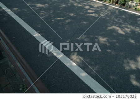 A road with sunlight filtering through the trees 108176022