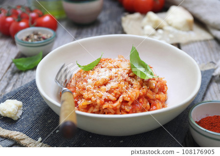 Italian cuisine. Plate of tomato risotto, olive oil, basil and cherry tomatoes Italian cuisine. Plate of tomato risotto, olive oil, basil and cherry tomatoes 108176905