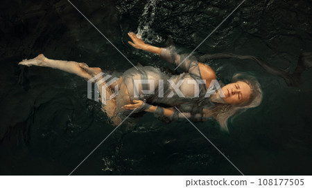 Portrait of a woman in a dress on a dark water surface Portrait of a woman in a dress on a dark water surface 108177505