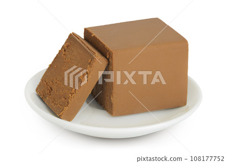 Brown cheese. Norwegian brunost in a ceramic bowl isolated on white background with full depth of field 108177752