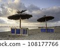Beach chairs and umbrellas, on a Spanish beach, put away for the evening	 108177766