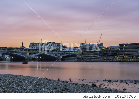 Blackfriars Bridge, London, UK, at sunset on a summer's evening. The sky is pink and orange, and it is reflecting in the River Thames Blackfriars Bridge, London, UK, at sunset on a summer's evening. The sky is pink and orange, and it is reflecting in the River Thames 108177769