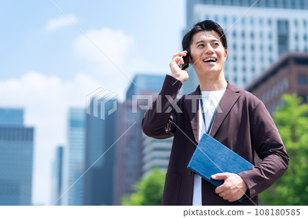A middle-aged male engineer working in an office area using a smartphone 108180585