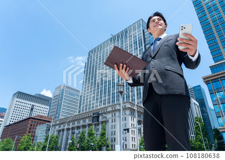 A middle-aged businessman commuting to the office while looking at his smartphone A middle-aged businessman commuting to the office while looking at his smartphone 108180638