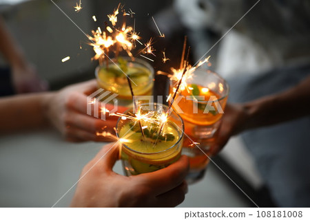 Young group friends hold in hand cocktail with sparkler 108181008