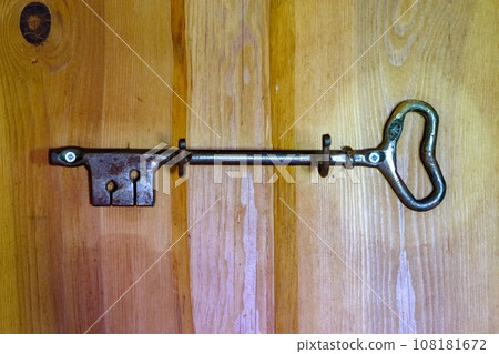 Old retro big rusty door key front wooden wall background. 108181672