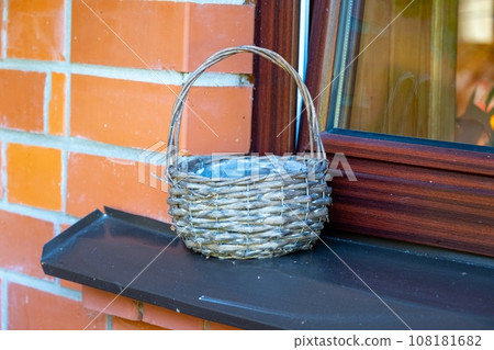 An empty wicker basket is placed on the windowsill outside An empty wicker basket is placed on the windowsill outside 108181682