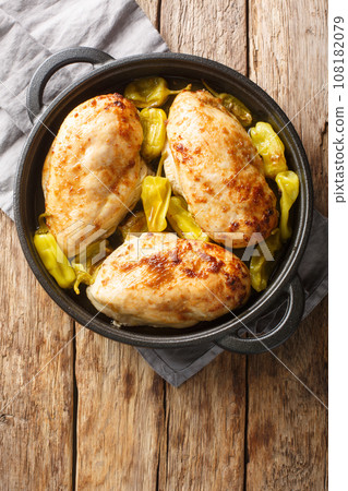 Baked chicken fillet with pepperoncini pepper close-up in a frying pan. Vertical top view Baked chicken fillet with pepperoncini pepper close-up in a frying pan. Vertical top view 108182079