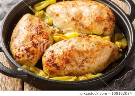 Home-baked chicken fillet with peperoncini peppers in a spicy sauce close-up in a frying pan. Horizontal Home-baked chicken fillet with peperoncini peppers in a spicy sauce close-up in a frying pan. Horizontal 108182084