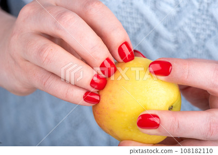 Woman's nails with manicure pierced the peel of an apple. Woman's nails with manicure pierced the peel of an apple. 108182110