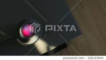 HomePod Mini speaker - the smart speaker is reacting to voice listening to human commands on the bedside table in the bedroom. Concept of a smart home. HomePod Mini speaker - the smart speaker is reacting to voice listening to human commands on the bedside table in the bedroom. Concept of a smart home. 108183044