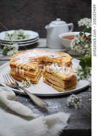 French cuisine. Matefaim. Stack of sweet Apple Pancakes, cup of tea and white spring flowers French cuisine. Matefaim. Stack of sweet Apple Pancakes, cup of tea and white spring flowers 108183484