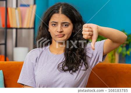 Upset Arabian woman showing thumbs down, dislike bad work, disapproval dissatisfied feedback at home Upset Arabian woman showing thumbs down, dislike bad work, disapproval dissatisfied feedback at home 108183785