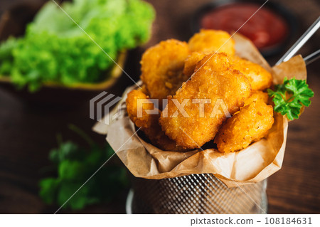 Semifinished Breaded chicken nuggets from chicken fillet on a dark background with fresh herbs. Quick cooking at home. Fast food. Breaded Chicken Inner Fillet. Fast cooking.Chicken nuggets with salad. Semifinished Breaded chicken nuggets from chicken fillet on a dark background with fresh herbs. Quick cooking at home. Fast food. Breaded Chicken Inner Fillet. Fast cooking.Chicken nuggets with salad. 108184631