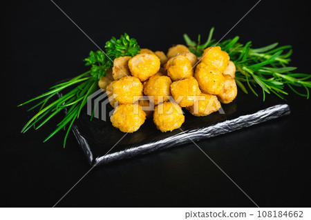 Semifinished chicken nuggets from chicken fillet on a dark background with fresh herbs. Quick cooking at home. Fast food. Breaded chicken nuggets. Breaded Chicken Inner Fillet. 108184662