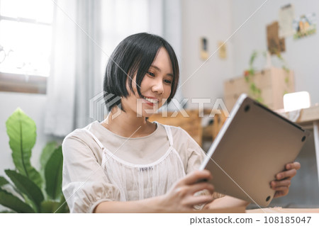 Asian woman unpack parcel box for new laptop in cozy bedroom 108185047