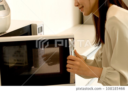 young asian woman using microwave young asian woman using microwave 108185466