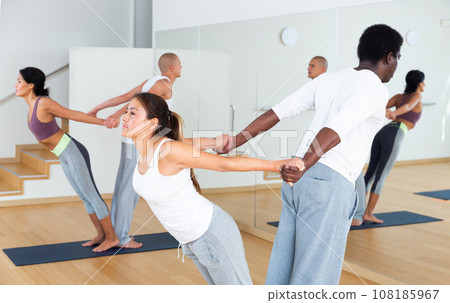 Couples practicing yoga with partner at studio 108185967