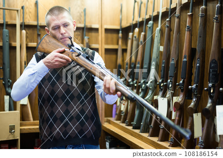 Buyer selects combat rifle at a gun store Buyer selects combat rifle at a gun store 108186154