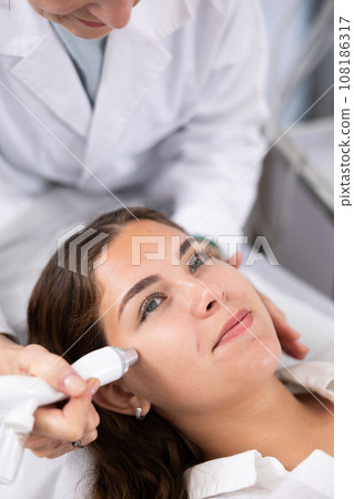 Young woman having face vacuum cleaning procedure Young woman having face vacuum cleaning procedure 108186317