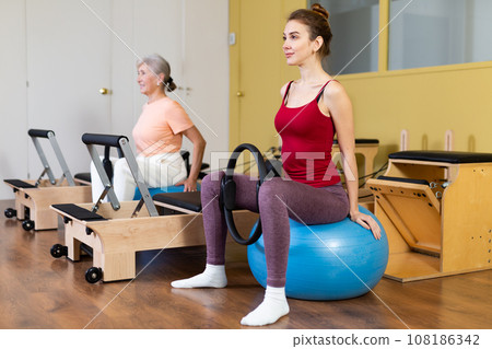 Active women perform exercises with fitness balls and Pilates rings 108186342