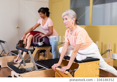 Elderly woman doing exercises on wunda chair in pilates studio Elderly woman doing exercises on wunda chair in pilates studio 108186352