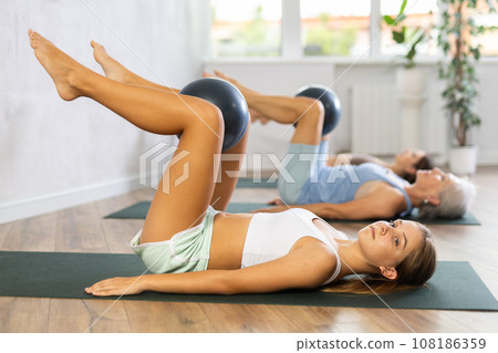 Teenage girl exercising with ball during group workout 108186359