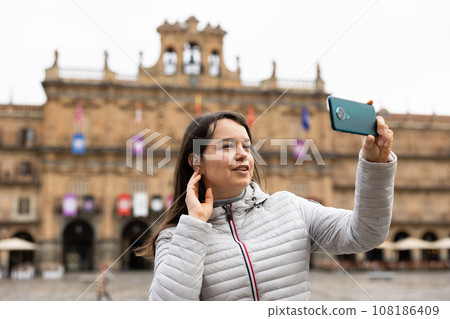 Woman is taking photos on her camera while journey through the Plaza Mayor. Spain 108186409
