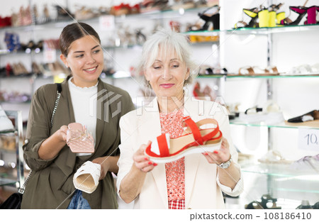 Elderly woman consults a young woman to buy summer shoes 108186410