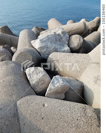 The scene with breakwaters and walls against the background of the sea. The scene with breakwaters and walls against the background of the sea. 108186460