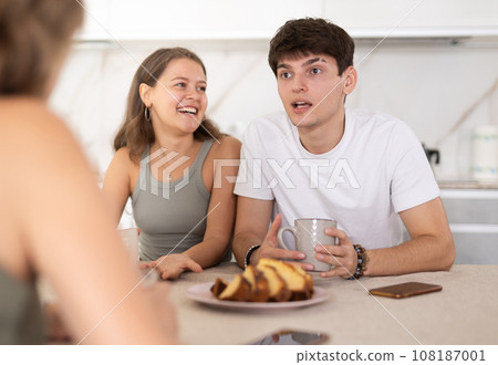 Mother having good time with adult children drinking tea in live room Mother having good time with adult children drinking tea in live room 108187001