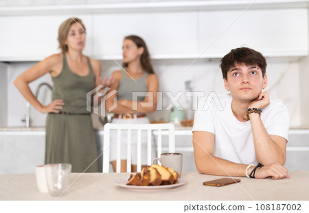 Bored guy is sitting at kitchen and unwittingly listens to mothers altercation with adult daughter Bored guy is sitting at kitchen and unwittingly listens to mothers altercation with adult daughter 108187002