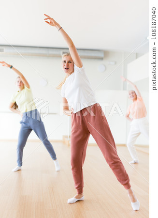 Woman dancing modern dance with other women during group training in classroom 108187040