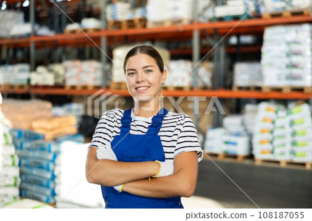 Positive warehouse girl employee stands with arms crossed over chest. 108187055