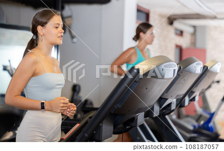 Focused motivated girl leading healthy active lifestyle doing cardio workout in gym, running on treadmill Focused motivated girl leading healthy active lifestyle doing cardio workout in gym, running on treadmill 108187057