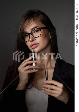 beautiful woman holding eyelashes tweezers on black background beautiful woman holding eyelashes tweezers on black background 108187197