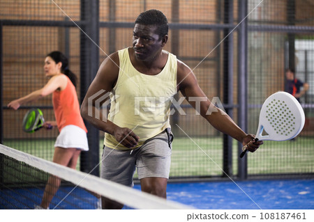 Sporty afro american man playing padel tennis indoor 108187461
