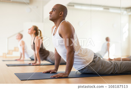 Hispanic man performing stretching asana Urdhva Mukha Shvanasana Hispanic man performing stretching asana Urdhva Mukha Shvanasana 108187513