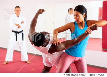 Woman training together with african american man in self defense lessons Woman training together with african american man in self defense lessons 108187581