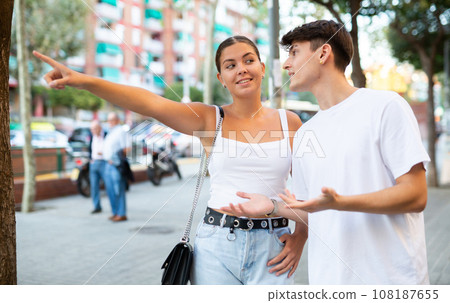 Happy young couple pointing while looking at something on city street 108187655