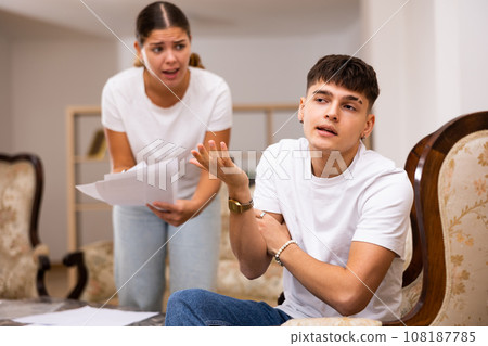 Upset young wife with documents swears at her husband 108187785