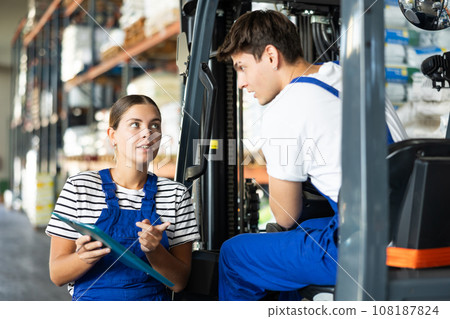 Guy drive operate automatic fork lift loader and answers young female auditors questions. Guy drive operate automatic fork lift loader and answers young female auditors questions. 108187824