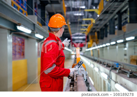 Back of professional technician worker with safety uniform point to the electrical train in factory 108189278