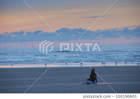 Girl meditating on the beach at sunset in the Netherlands 108190603