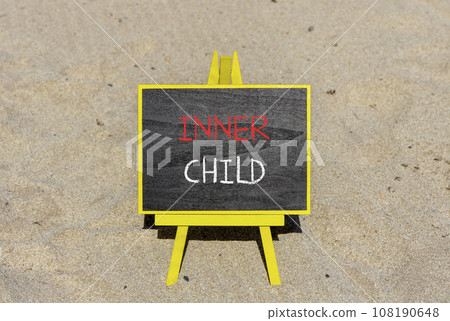 Inner child symbol. Concept words Inner child on beautiful black chalk blackboard. Beautiful sea sand beach background. Psychological, motivational inner child concept. Copy space. Inner child symbol. Concept words Inner child on beautiful black chalk blackboard. Beautiful sea sand beach background. Psychological, motivational inner child concept. Copy space. 108190648