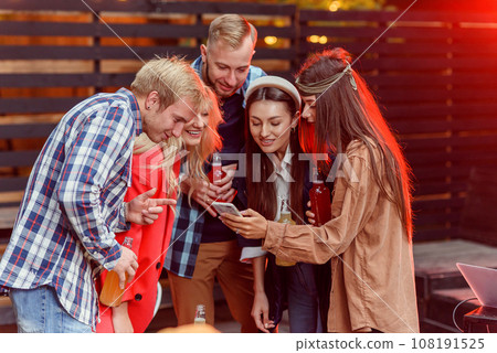 Group of happy young friends enjoying weekend at the party using smartphone sharing selfie photo on social networks. Group of happy young friends enjoying weekend at the party using smartphone sharing selfie photo on social networks. 108191525