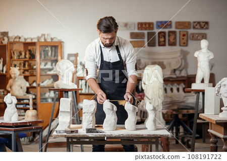 Male craftsman in working uniform makes a limestone copy of woman torso at the creative studio and show making process from start to finish. 108191722